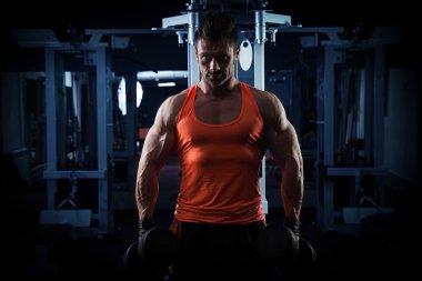 Spor salonunda ağırlık kaldıran genç bir vücut geliştirici..