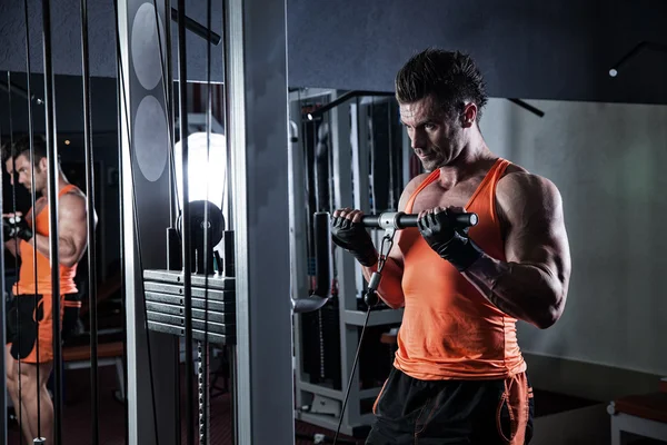 Spor salonunda ağırlık kaldıran genç bir vücut geliştirici..