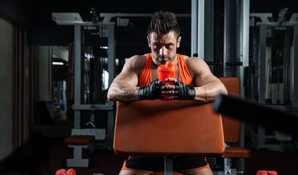 Bello giovane uomo muscoloso beve una proteina in palestra — Foto Stock