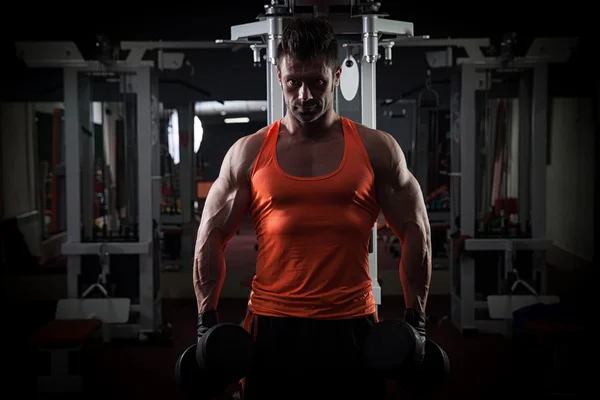 Culturista adulto joven haciendo levantamiento de pesas en el gimnasio. —  Fotos de Stock