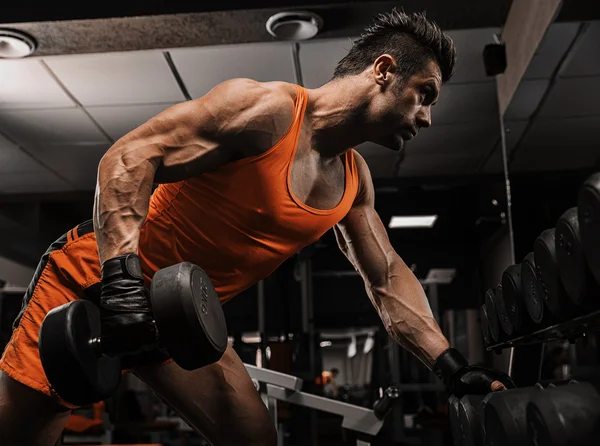 Very power athletic guy standing with barbell, workout in the gy — Stock Photo, Image