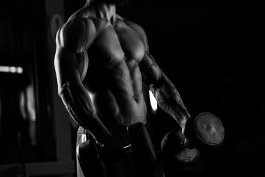 Güçlü adam - bir spor salonunda dumbbells ile vücut geliştirmeci zekâ egzersiz