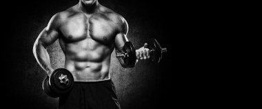 Yakışıklı ve kaslı bir adam, spor salonunda kameraya poz veriyor.