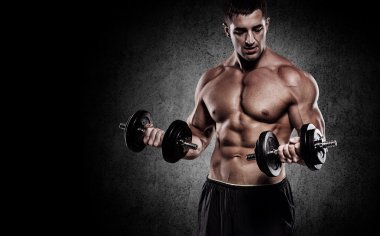 güçlü ve yakışıklı bir genç adam dumbbells ile egzersiz yaparak