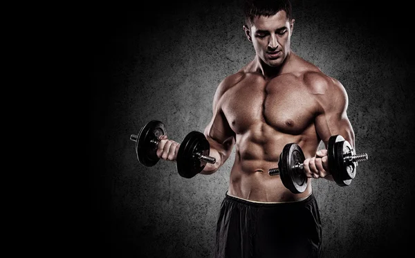 Güçlü ve yakışıklı bir genç adam dumbbells ile egzersiz yaparak — Stok fotoğraf