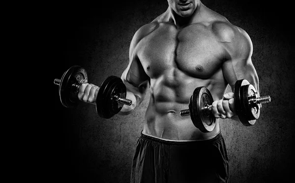 Güçlü ve yakışıklı bir genç adam dumbbells ile egzersiz yaparak — Stok fotoğraf