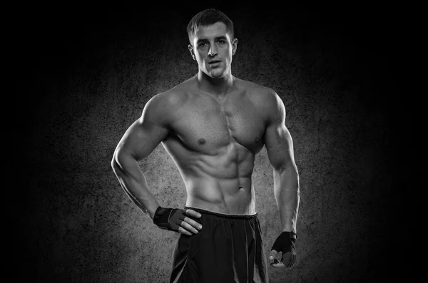 Portrait of a handsome muscular bodybuilder posing over black ba — Stock Photo, Image