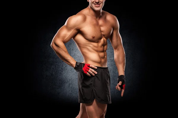 Doing exercises for biceps, on a dark background in the studio — Stock Photo, Image