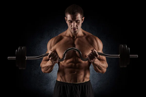 Wykonywanie ćwiczeń na biceps, na ciemnym tle w studio — Zdjęcie stockowe