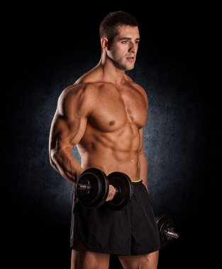 kaslı vücut geliştirmeci biri dumbbells ile yapıyor