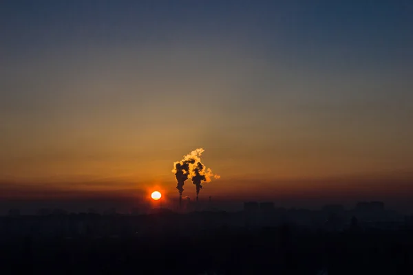 Schoorstenen en donkere rook fabriek bij zonsondergang over — Stockfoto