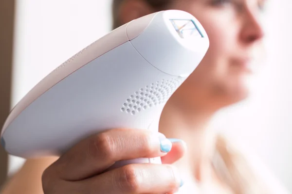 Young blond woman holding a appliance for photo-epilation — Stock Photo, Image