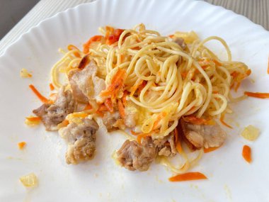 Beyaz tabakta etli ve sebzeli makarna.