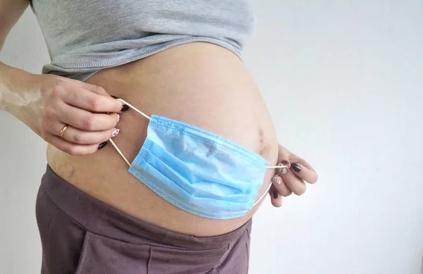Der Bauch Einer Schwangeren Frau Mit Medizinischer Maske Großaufnahme Ist — Stockfoto