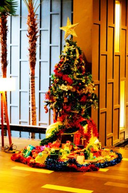 Parlak Noel ağacı süsleri ve hediyeleriyle tepesinde altın bir yıldızla