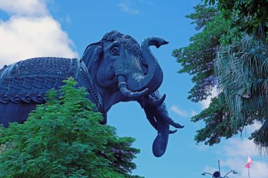  Dev Fil Heykeli, bulutlu mavi gökyüzünün arka planında, ağaçların tepesinde ortaya çıktı.