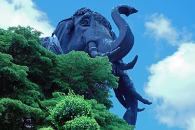  Dev Fil Heykeli, bulutlu mavi gökyüzünün arka planında, ağaçların tepesinde ortaya çıktı.