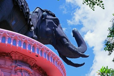 Mavi gökyüzü arka planındaki pembe balkonda dev bir fil heykelinin başı..