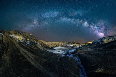 Paisaje de crater con nieve y via lactea en cielo azul