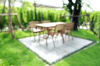 Ahşap sandalyeli bulanık bir köşe ve açık hava yeşil arka plan.