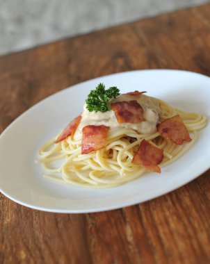Ahşap masada domuz pastırmalı lezzetli spagetti carbonara.