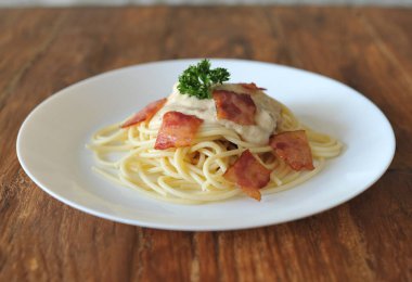 Ahşap masada domuz pastırmalı lezzetli spagetti carbonara.