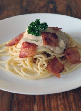 Ahşap masada domuz pastırmalı lezzetli spagetti carbonara.