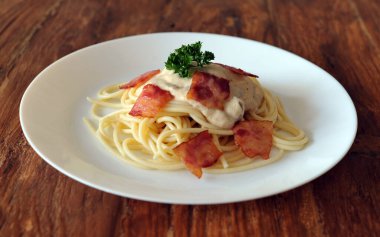 Ahşap masada domuz pastırmalı lezzetli spagetti carbonara.