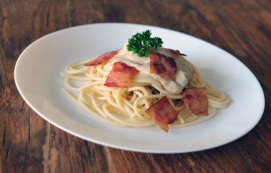 Ahşap masada domuz pastırmalı lezzetli spagetti carbonara.