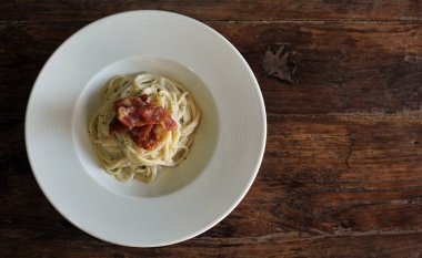 Ahşap masada domuz pastırmalı lezzetli spagetti carbonara.
