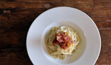 Ahşap masada domuz pastırmalı lezzetli spagetti carbonara.