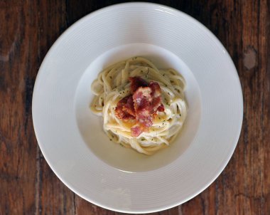 Ahşap masada domuz pastırmalı lezzetli spagetti carbonara.