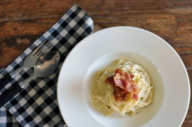 Ahşap masada domuz pastırmalı lezzetli spagetti carbonara.