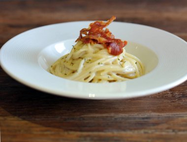 Ahşap masada domuz pastırmalı lezzetli spagetti carbonara.