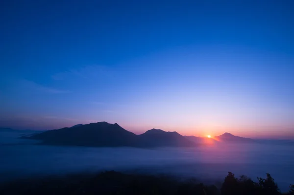 Salida del sol en la cima de la niebla de la montaña — Foto de Stock