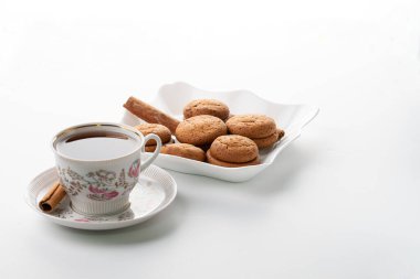 Bir fincan sıcak çay, tarçınlı kurabiyeler beyaz arka plan yüksek anahtarına özen gösterir.