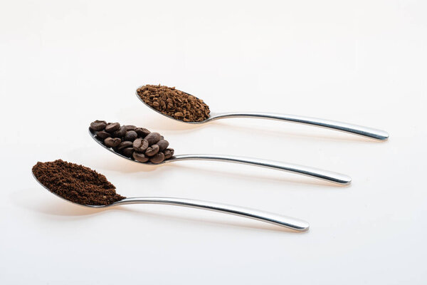 coffee beans ground instant each in its own teaspoon on a