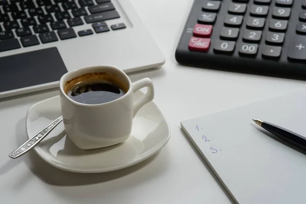 Beyaz arka planda bir fincan aromatik espresso kahve bilgisayar hesap makinesi kalem. Bugün için bir plan yapıyorum..