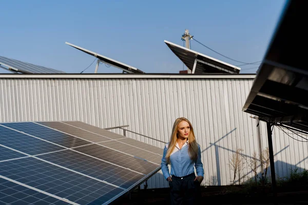Girl walks between 2 Solar panels row on the ground at sunset. Woman investor wears formal white shirt. Free electricity for home. Sustainability of planet. Green energy.