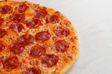 Beyaz ahşap arka planda izole edilmiş salamlı, peynirli ve soslu peperoni pizza. Lokantalar, kafeler için sosyal ağ ilanı. Pizzacı için tanıtım