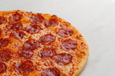 Beyaz ahşap arka planda izole edilmiş salamlı, peynirli ve soslu peperoni pizza. Lokantalar, kafeler için sosyal ağ ilanı. Pizzacı için tanıtım