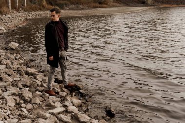 Turist ülkesini geziyor ve Coronavirus covid-19 karantinasının sonunu düşünüyor. Genç adam göl kenarında yürüyor ve hayatını düşünüyor..