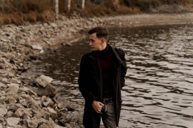 Avukat göl kenarında resmi siyah bir ceket giydi. Kendine güvenen adam Neak Gölü 'nde yürüyor