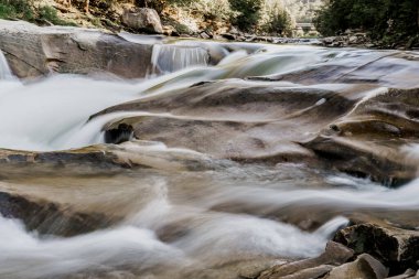 Bulanık suyla dolu bir şelale çünkü fotoğraf uzun süre çekim hızında çekildi. Dağ nehrinde büyük taşlı bir şelale. Karantina döneminde seyahat ediyorlar. Doğa manzarası. Karpatlar dağları