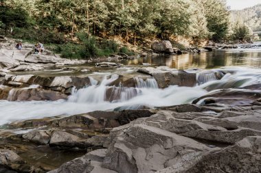 Bulanık suyla dolu bir şelale çünkü fotoğraf uzun süre çekim hızında çekildi. Dağ nehrinde büyük taşlı bir şelale. Karantina döneminde seyahat ediyorlar. Doğa manzarası. Karpatlar dağları