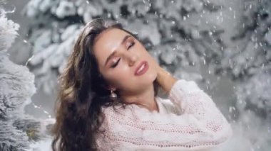 Yeni yıl kutlaması. Kar yağışı olan çekici bir kız. Sıcak beyaz kazak ve beyaz çorap giymiş genç bir kadın.