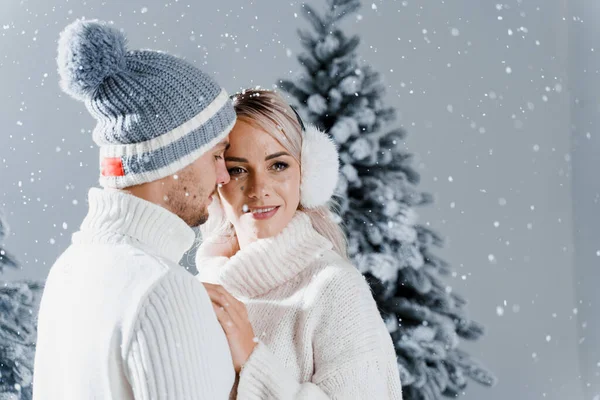 Feliz Pareja Joven Abrazos Sonrisas Nieve Cae Cerca Los Árboles — Foto de Stock