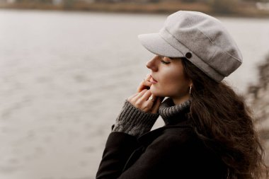 Gölün yanında siyah ceketli ve gri yün şapkalı güzel bir kız. Senin ülkende seyahat etmek