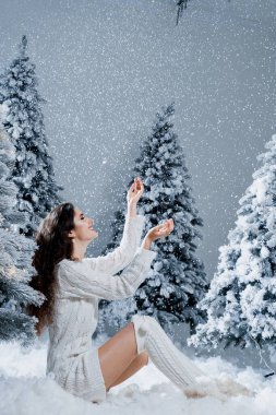 Mutlu kız yeni yıl arifesinde gülümser ve yağan kara dokunur. Genç bir kadın, kışın, büyük karlı çimlerin yanında Noel 'den önce