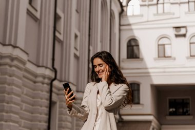 Kız internette akıllı telefon kullanarak servis yapıyor. Müdür telefonda çevrimiçi çalışıyor. Kıvırcık saçlı çekici bir kız şehirde izole edilmiş sosyal ağlarda telefonuna cevap veriyor.